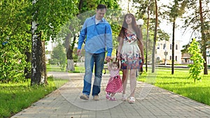 Little baby learning how to walk with mom and dad,happy family walking in summer Park