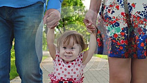 Little baby learning how to walk with mom and dad,happy family walking in summer Park