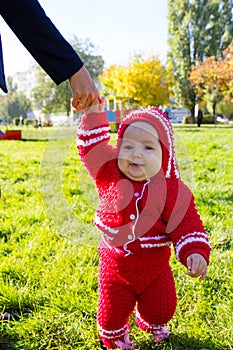 Little baby learning to walk. Mom holding baby's hand