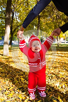 Little baby learning to walk. Mom holding the baby's hands