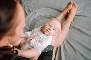 Little baby lies on mother`s feet and looks at the camera