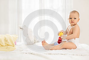 Little baby in nappy playing with toys