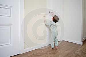 Little baby opens the door. Child pulls the door handle with the lock clo