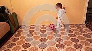 Little baby is playing with a ball. Happy kid carrying football smiling. Boy