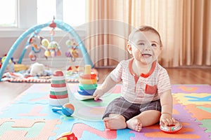 Little baby playing with toys on playmat at home. photo