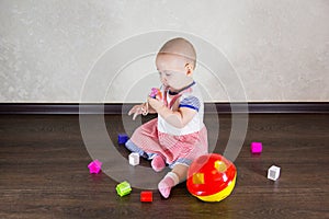 Little baby playing with toys. Small child chews on a toy