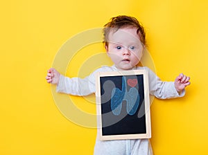 Little baby with X-ray board and drawing lungs and heart