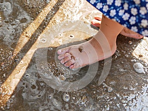 Little baby`s bare feet on wet ground, sand - letting your baby play in dirt could boost the child`s immune system