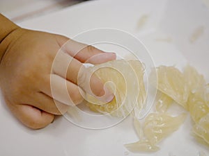 Little baby`s hand picking a piece of fruit, pomelo