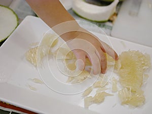 Little baby`s hand picking a piece of fruit, pomelo