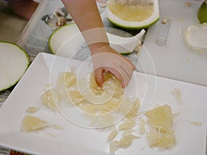 Little baby`s hand picking a piece of fruit, pomelo