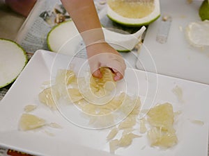 Little baby`s hand picking a piece of fruit, pomelo