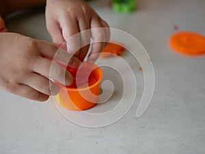 Little baby`s hands collecting and putting playdough back into the box, after finish playing