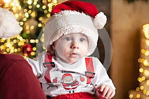 Little baby in Santa hat celebrates Christmas. Infant in New Year red cap. Xmas greeting card with cute babies.