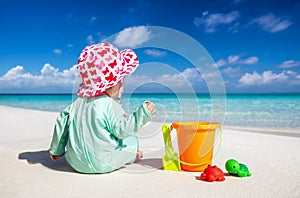 Little baby sits on a tropical beach and plays