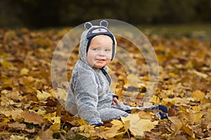 Little baby sitting in yellow and orange autumn leaves.