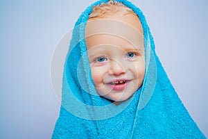 Little baby smiling under a white towel. Small little cute sweet blonde boy bathes in a bath.