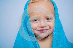 Little baby smiling under a white towel. Smiling baby boy bathing under a shower at home. Happy bath time.