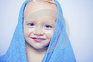 Little baby smiling under a white towel. Smiling baby boy bathing under a shower at home. Happy bath time.