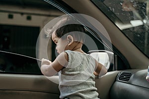 Little baby stand in the car when the windows are opened