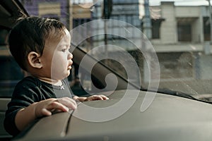 Little baby standing on car dashboard looking ahead