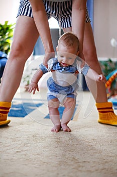 Little baby takes the first steps with the support of the mother, the child learns to walk, trainin