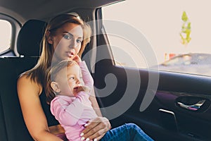 Little baby toddler girl looks out of the car window with her mom.