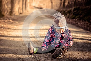 Little baby toddler sitting and playing on road in winter