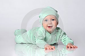 Little baby toddler wearing body set of slider and hat crawling on floor over white background.
