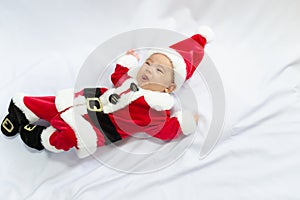 Little baby wearing red Santa Claus costume sleep on white fur carpet. Concept of celebrates Christmas and New Year