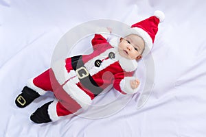 Little baby wearing red Santa Claus costume sleep on white fur carpet. Concept of celebrates Christmas and New Year