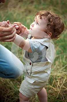 The little baby or year-old child on the grass in sunny summer day.