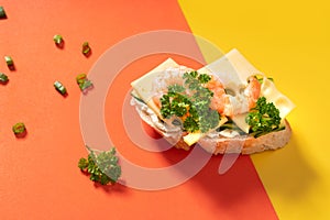 Little baguette sandwiches on vibrant yellow and orange background decorated with greens