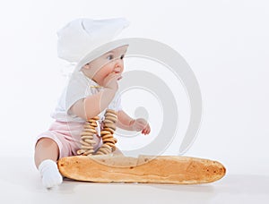 Little baker baby girl with a long loaf and bagels.