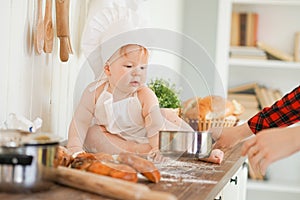 Little baker child in chef hat at kitchen table alone