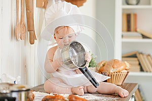 Little baker child in chef hat at kitchen table alone