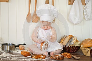 Little baker child in chef hat at kitchen table alone