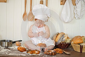 Little baker child in chef hat at kitchen table alone