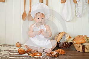 Little baker child in chef hat at kitchen table alone