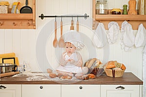 Little baker child in chef hat at kitchen table alone