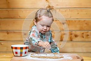 Little baker child at kitchen. Baby boy in the kitchen helping with cooking, playing with flour.