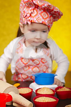 Little baker or cook girl cuts dough for cookies