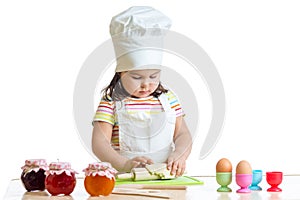 Little baker kid girl in chef hat at kitchen