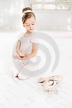 The little balerina in white tutu in class at the ballet school