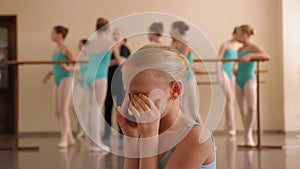 A little ballerina cries in a ballet dance Studio during a class.