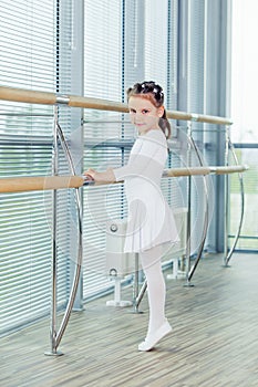 Little ballerina girl. Adorable child dancing classical ballet in a white studio.