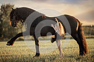 Little ballerina girl with black friesian stallion