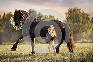 Little ballerina girl with black friesian stallion