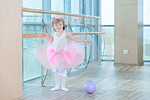 Little ballerina girl in a pink tutu. Adorable child dancing classical ballet in a white studio. Children dance. Kids