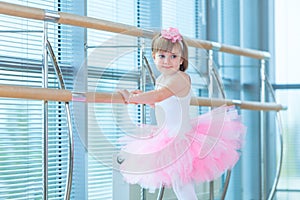 Little ballerina girl in a pink tutu. Adorable child dancing classical ballet in a white studio. Children dance. Kids